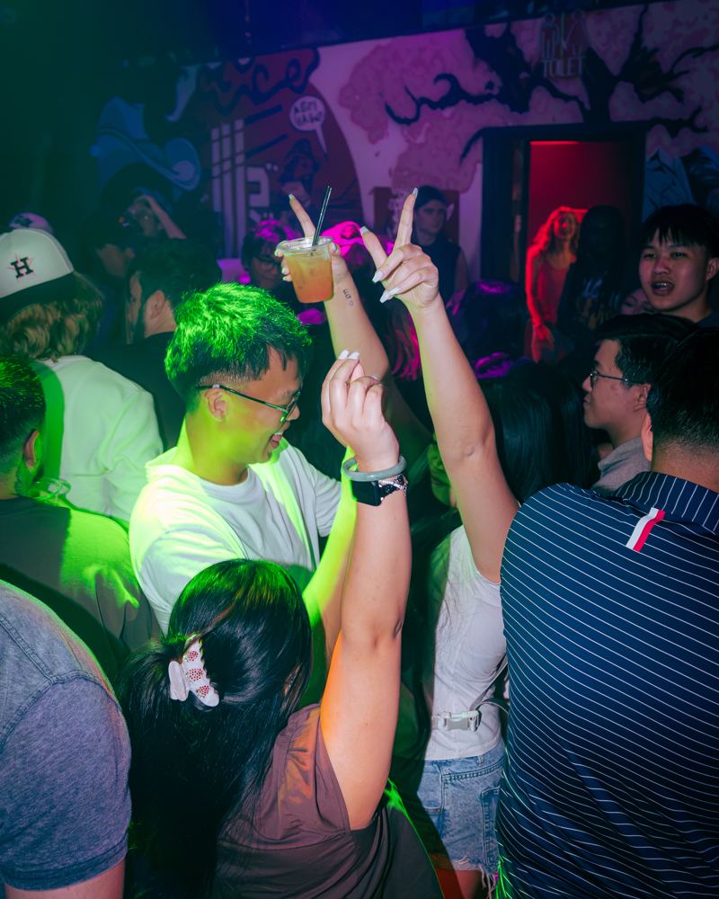 Crowd with hands up under green light at Tokyo Joe's